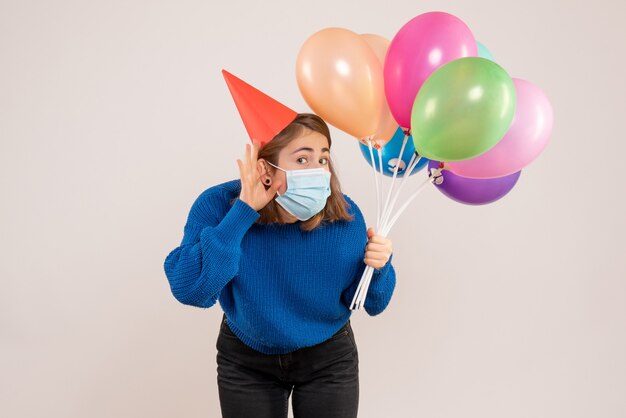 giovane donna in possesso di palloncini colorati in maschera su bianco