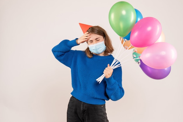 giovane donna in possesso di palloncini colorati in maschera su bianco