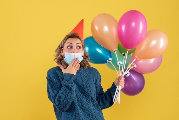 giovane donna in possesso di palloncini colorati su giallo