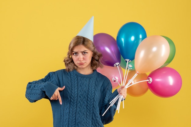 giovane donna in possesso di palloncini colorati su giallo