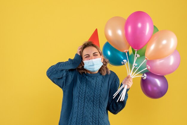 giovane donna in possesso di palloncini colorati su giallo