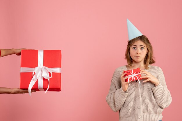 giovane donna in possesso di regalo di Natale e di accettare da maschio in rosa