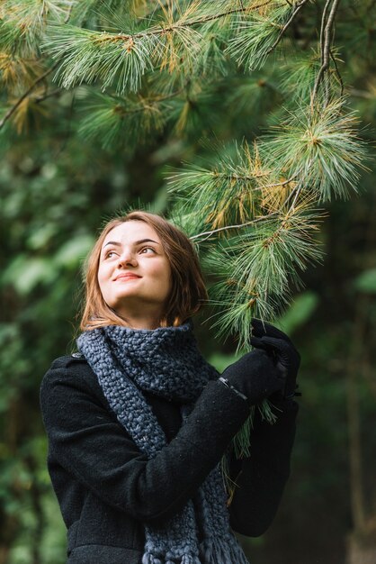 Giovane donna in sciarpa conifero ramoscello