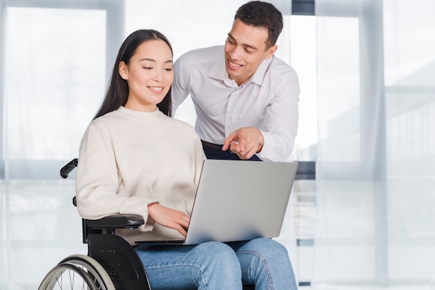 Giovane donna in sedia a rotelle, lavorando con un collega di sesso maschile