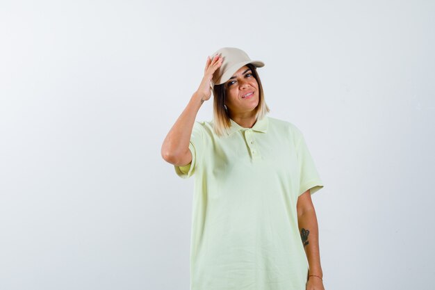 Giovane donna in t-shirt, cappuccio che tiene la mano sul cappuccio mentre posa e sembra sicura, vista frontale.