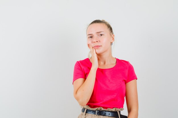 Giovane donna in t-shirt che soffre di mal di denti e che sembra a disagio