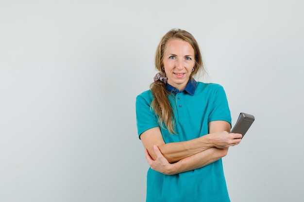 Giovane donna in t-shirt che tiene il calcolatore e che sembra allegro