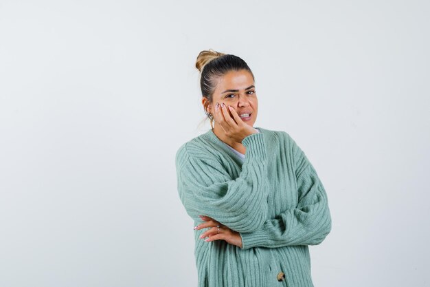 Giovane donna in t-shirt, giacca appoggiata al mento sul palmo e dall'aspetto carino