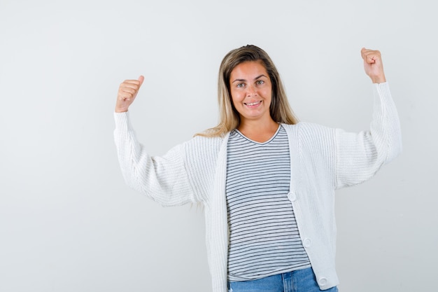 Giovane donna in t-shirt, giacca che mostra i muscoli delle braccia e guardando fiducioso, vista frontale.