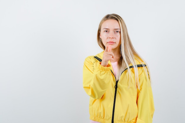 Giovane donna in t-shirt, giacca che punta la fotocamera e sembra sicura