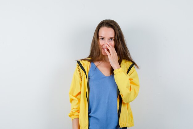 Giovane donna in t-shirt in posa toccandosi il naso e sembrando seducente