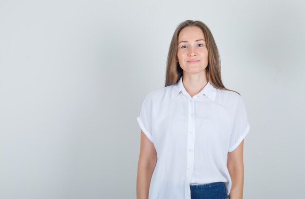 Giovane donna in t-shirt, jeans in piedi e sorridente