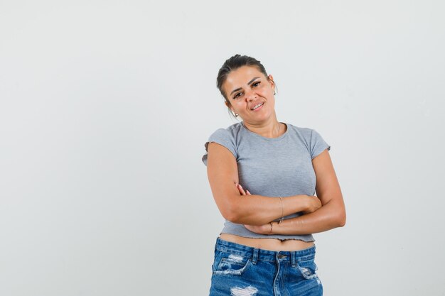 Giovane donna in t-shirt, pantaloncini in posa in piedi e in cerca affascinante