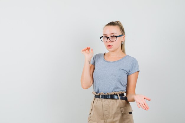 Giovane donna in t-shirt, pantaloni che sembrano confusi, vista frontale.