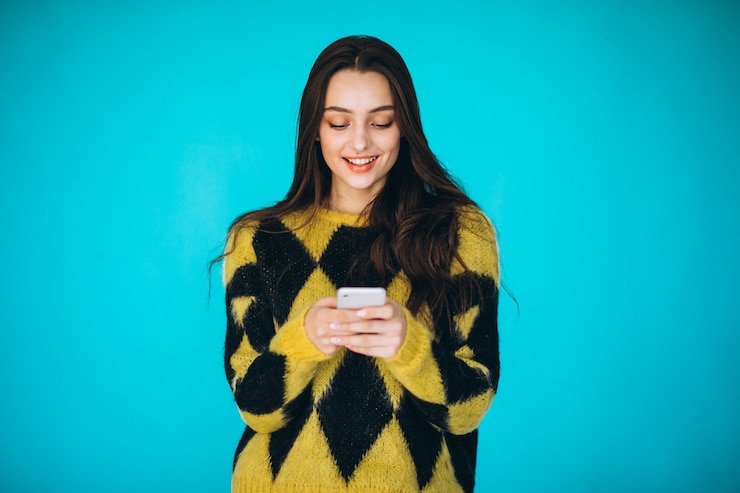 Foto gratuito giovane donna in un maglione caldo utilizzando il telefono