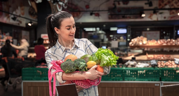 Giovane donna in un supermercato con frutta e verdura che acquistano generi alimentari