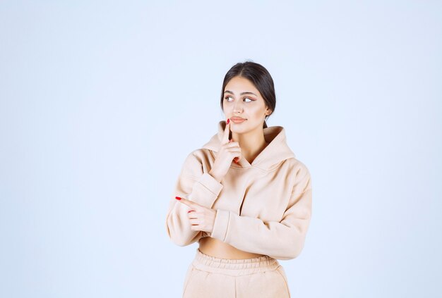 Giovane donna in una felpa con cappuccio rosa pensando e il brainstorming