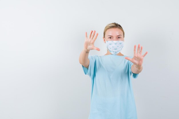 Giovane donna in una maglietta blu con una maschera medica