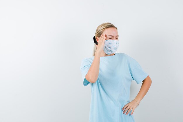 Giovane donna in una maglietta blu con una maschera medica