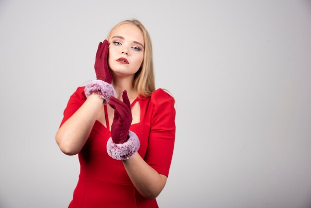 Giovane donna in vestito rosso che propone alla macchina fotografica.