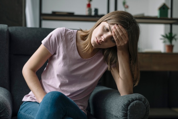 Giovane donna infelice che si siede sulla poltrona