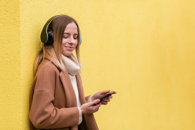 Giovane donna moderna che ascolta la musica sulle cuffie con lo spazio della copia