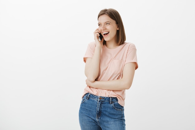 Giovane donna moderna spensierata che parla sul telefono cellulare felice, ridendo