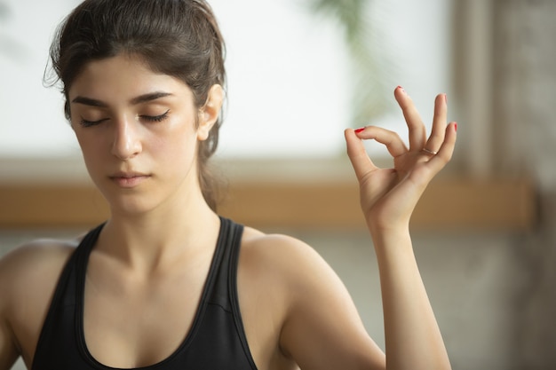 Giovane donna musulmana sportiva che prende lezioni di yoga a casa