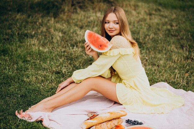 Giovane donna nel parco mangiando anguria