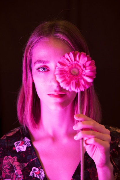 Giovane donna premurosa con la gerbera rosa