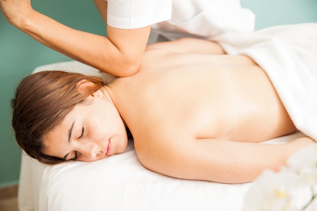 Giovane donna rilassata che riceve un massaggio dei tessuti profondi da una terapista femminile in una clinica sanitaria, vista da vicino