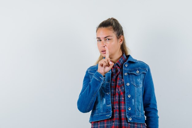 Giovane donna rivolta verso l'alto in camicia, giacca e sguardo intelligente, vista frontale.