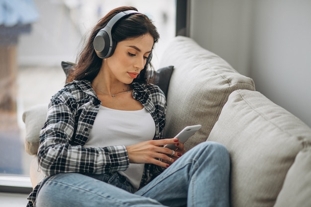 Giovane donna sdraiata sul divano in cuffia ascoltando musica