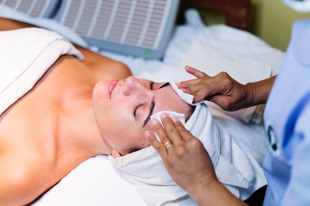 Giovane donna sdraiata sul tavolo del cosmetologo durante la procedura di ringiovanimento