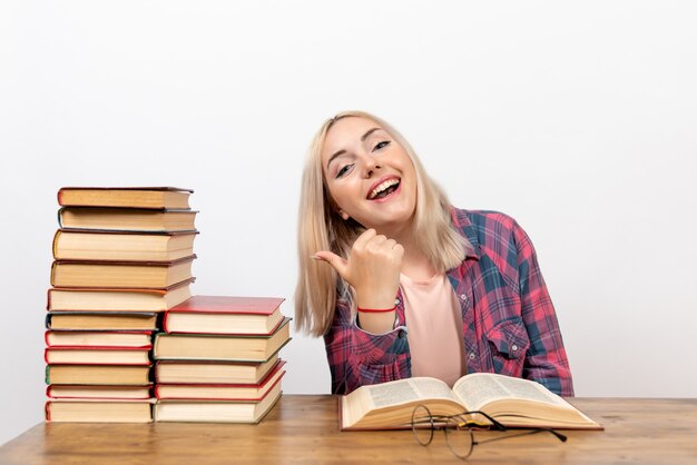 giovane donna seduta con libri e lettura su bianco