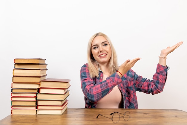 giovane donna seduta con libri su bianco