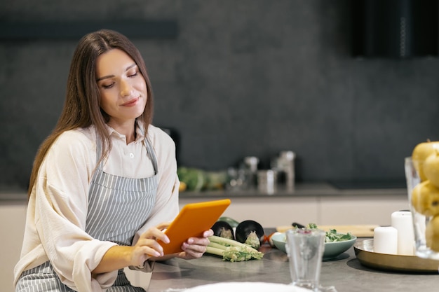 Giovane donna seduta in cucina e guardando pensierosa