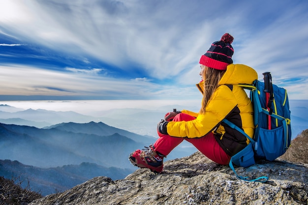 Giovane donna seduta sulla collina di alte montagne