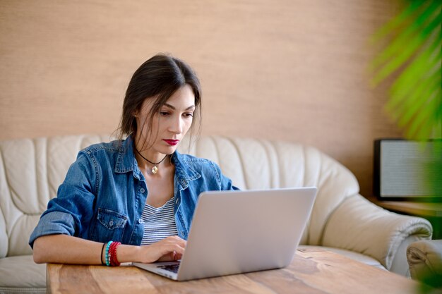 Giovane donna seria che lavora ad un computer portatile in ufficio