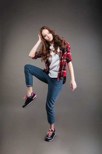 Giovane donna seria nel ballare della camicia e dei jeans di plaid