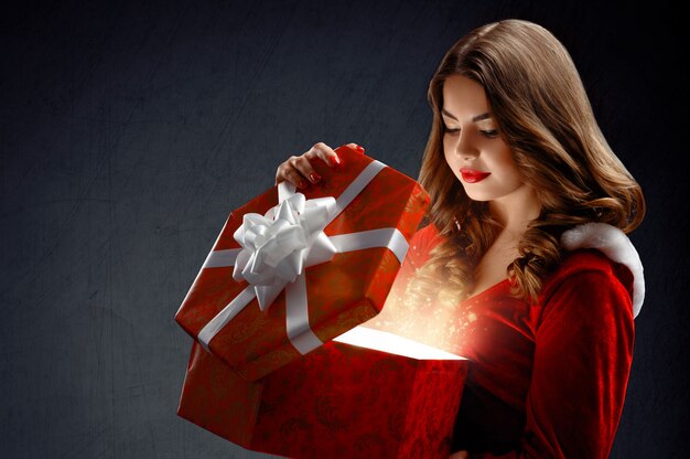 Giovane donna sexy in abito rosso di Babbo Natale con doni. Su un da