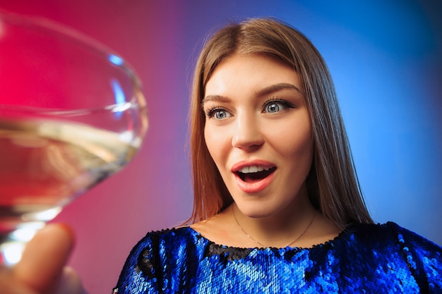 giovane donna sorpresa in abiti da festa in posa con un bicchiere di vino