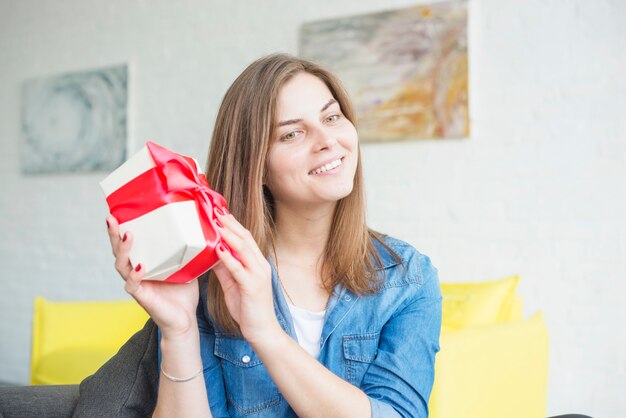 Giovane donna sorridente che agita il contenitore di regalo