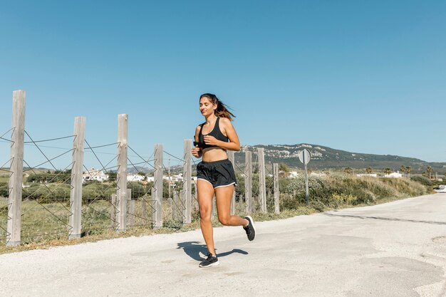 Giovane donna sorridente che corre lungo la strada