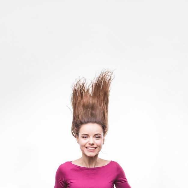 Giovane donna sorridente che getta i suoi capelli castana