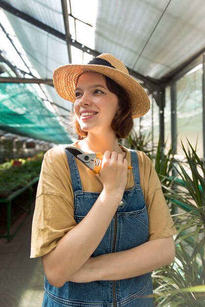 Giovane donna sorridente che lavora in una serra