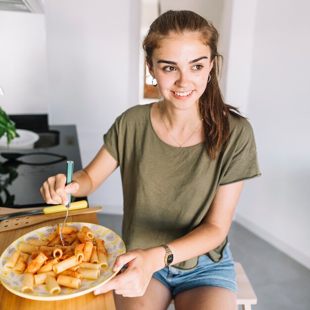 Giovane donna sorridente che mangia pasta casalinga