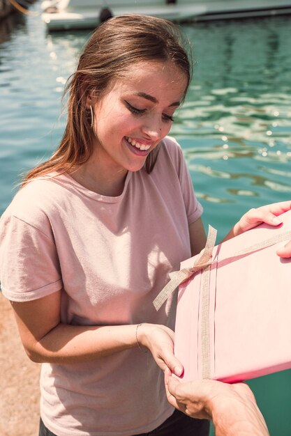 Giovane donna sorridente che riceve regalo dal suo fidanzato al porto