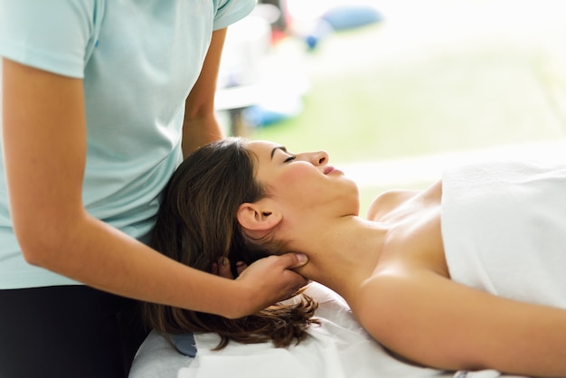 Giovane donna sorridente che riceve un massaggio alla testa in un centro benessere.