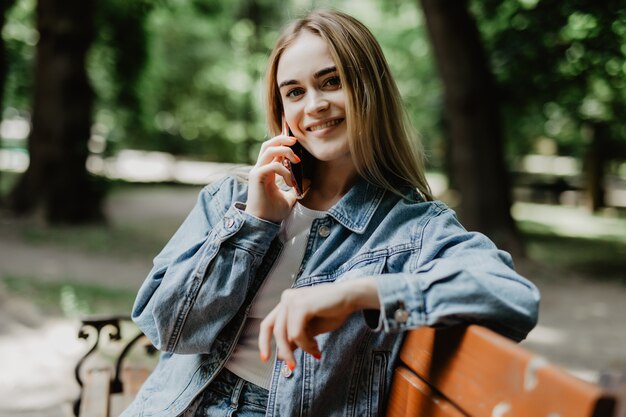 Giovane donna sorridente che rivolge allo smartphone sulla via della città